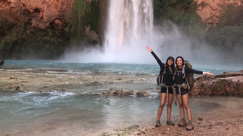 Two hikers at the bottom of a waterfall near Supai in Arizona